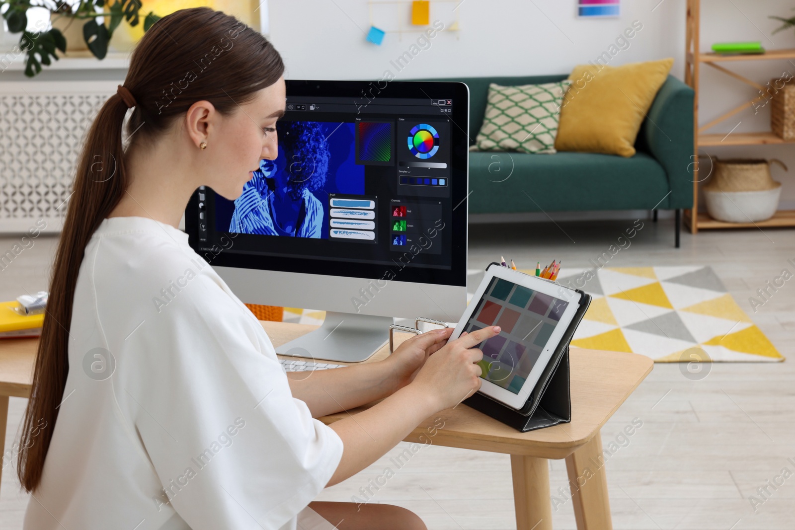 Photo of Designer working on tablet at wooden table indoors