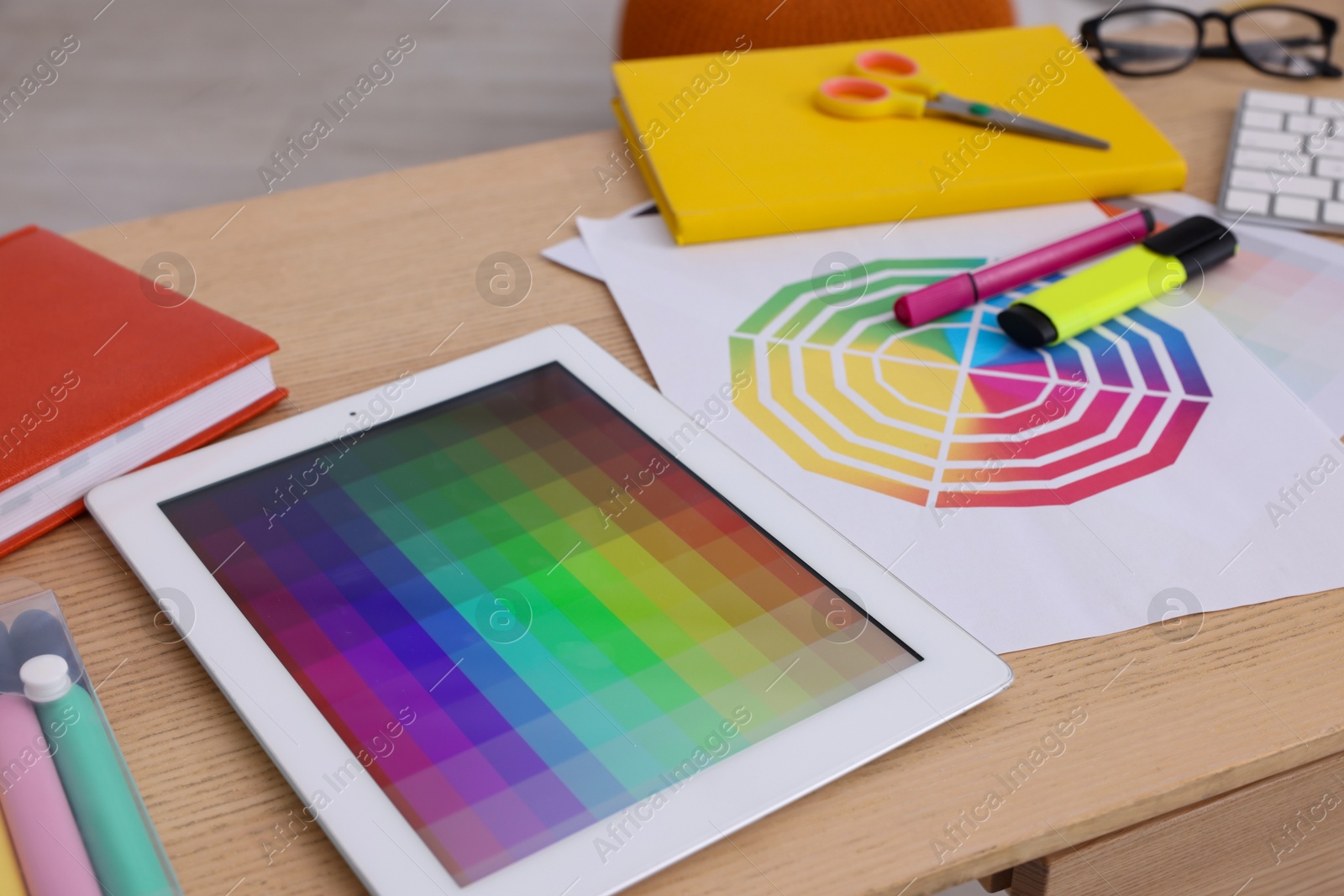 Photo of Designer's workplace with tablet, color palette and stationery on wooden table, closeup