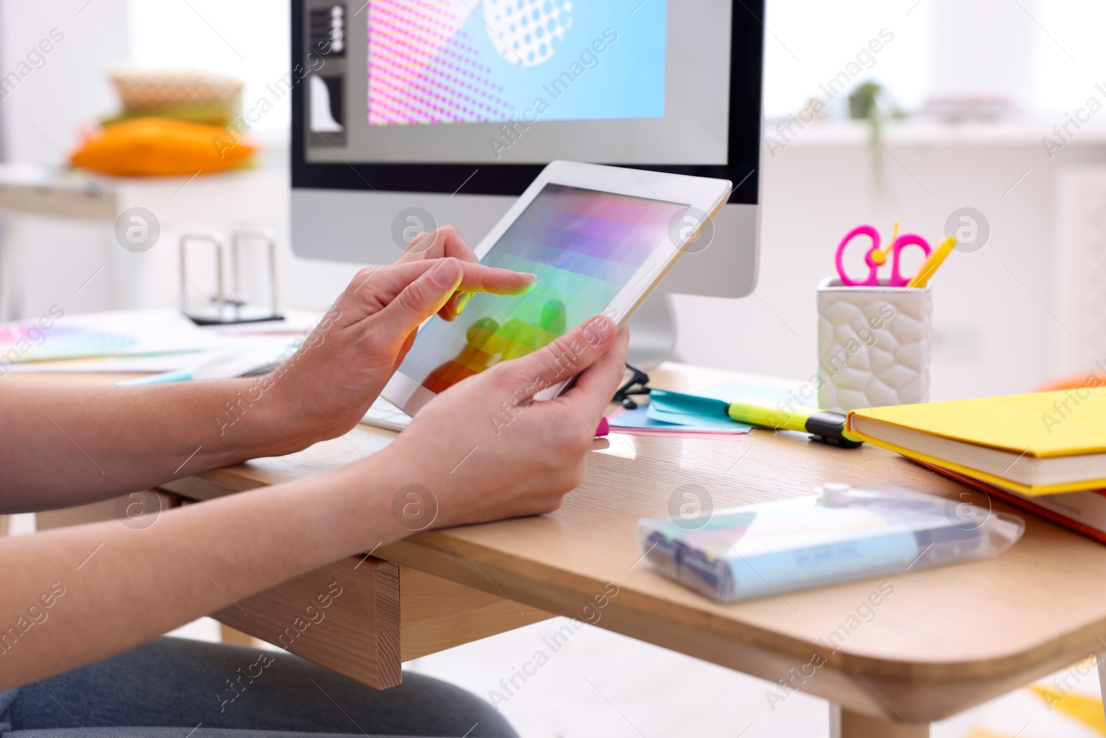 Photo of Designer working on tablet at wooden table indoors, closeup