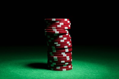 Photo of Poker game. Stack of casino chips on green table against dark background