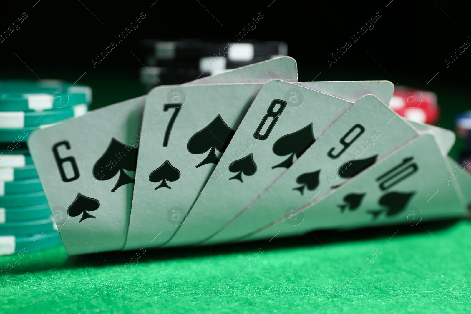 Photo of Playing cards and poker chips on green table, closeup