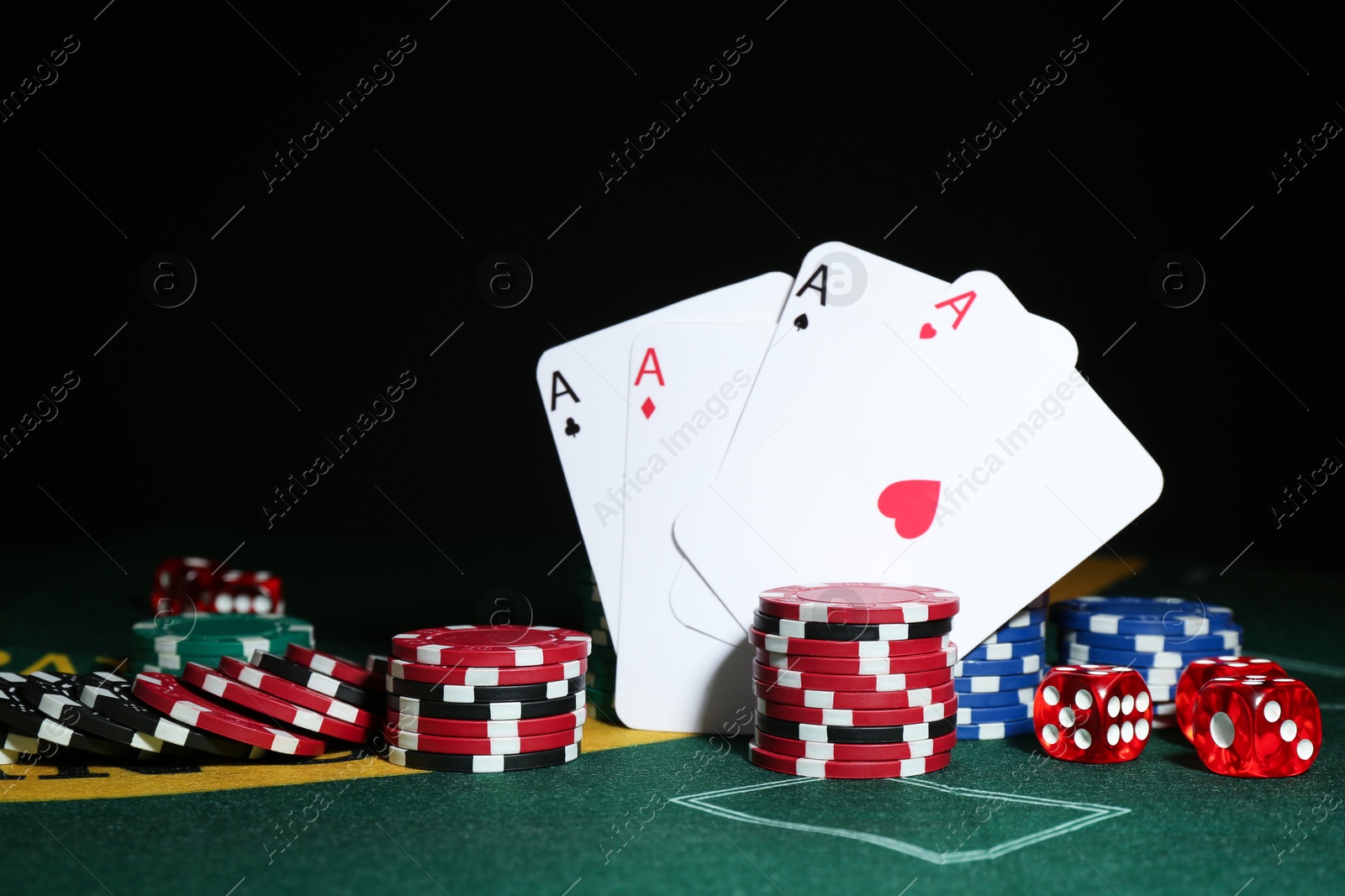 Photo of Poker chips, dices and playing cards on green table