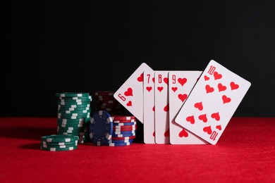 Poker chips and playing cards on red table