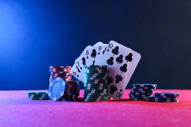 Poker chips and playing cards on pink table