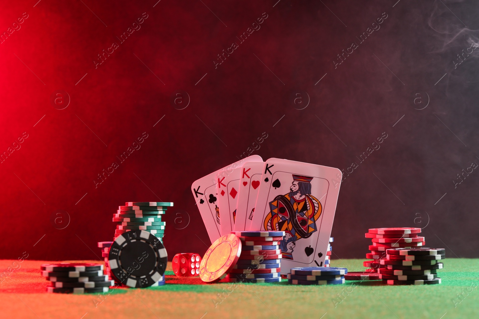 Photo of Poker chips, dice and playing cards on green table in neon lights