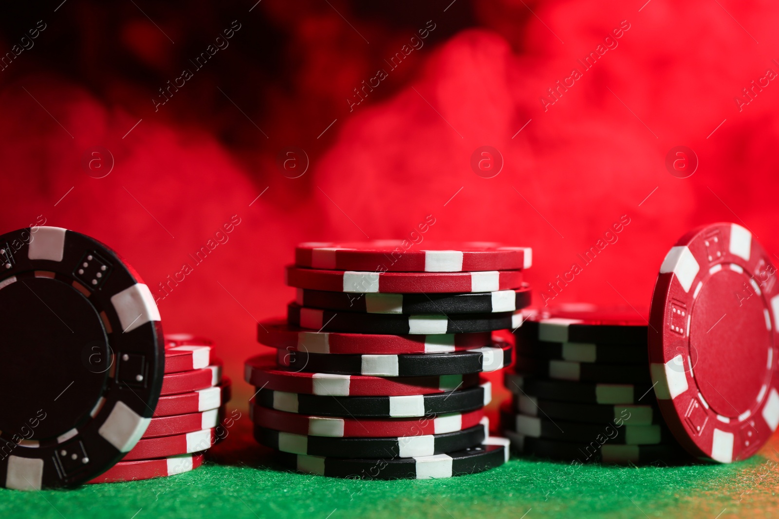 Photo of Poker game. Casino chips on green table in neon lights, closeup