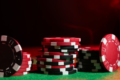 Photo of Poker game. Casino chips on green table in neon lights, closeup