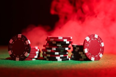 Poker game. Casino chips on green table in neon lights, closeup