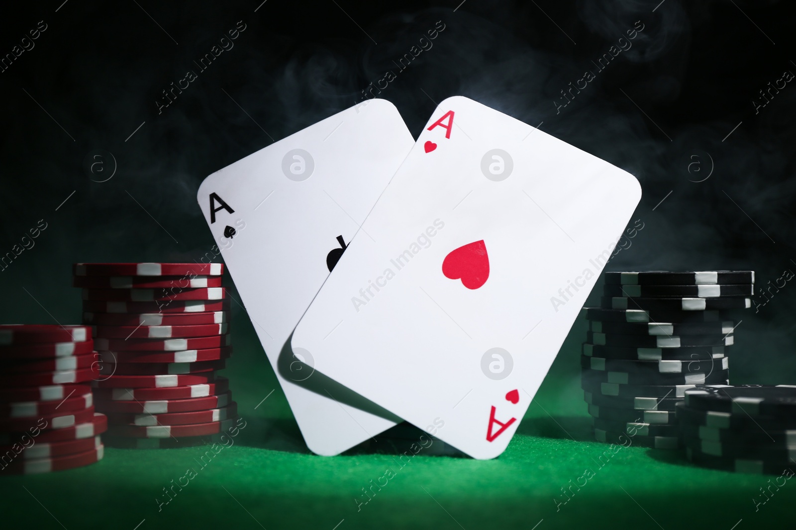 Photo of Poker chips and playing cards on green table, closeup