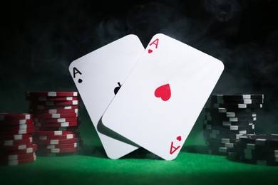 Photo of Poker chips and playing cards on green table, closeup