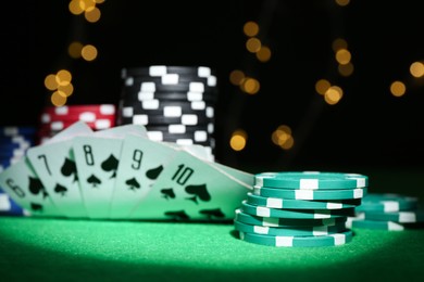 Photo of Poker chips and playing cards on green table, closeup