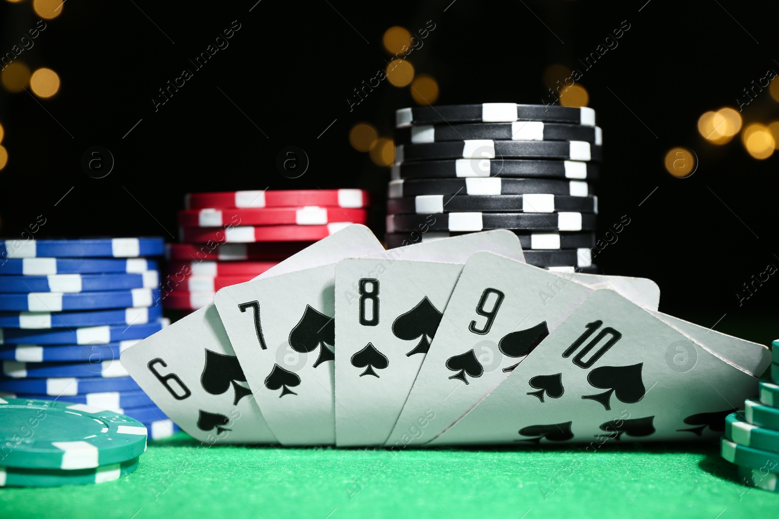 Photo of Poker chips and playing cards on green table, closeup