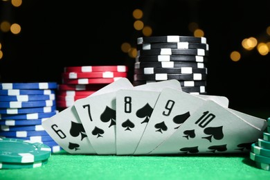 Photo of Poker chips and playing cards on green table, closeup