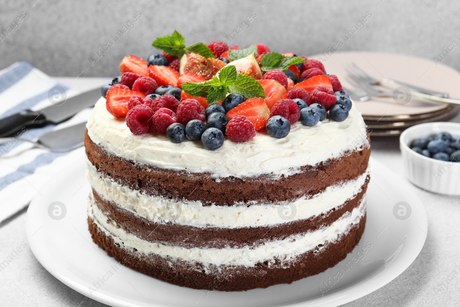 Photo of Delicious chocolate sponge cake with berries served on light table, closeup