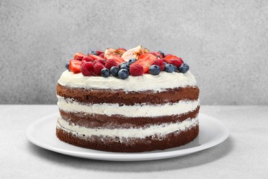 Photo of Delicious chocolate sponge cake with berries on light table