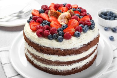 Photo of Delicious chocolate sponge cake with berries served on light table, closeup