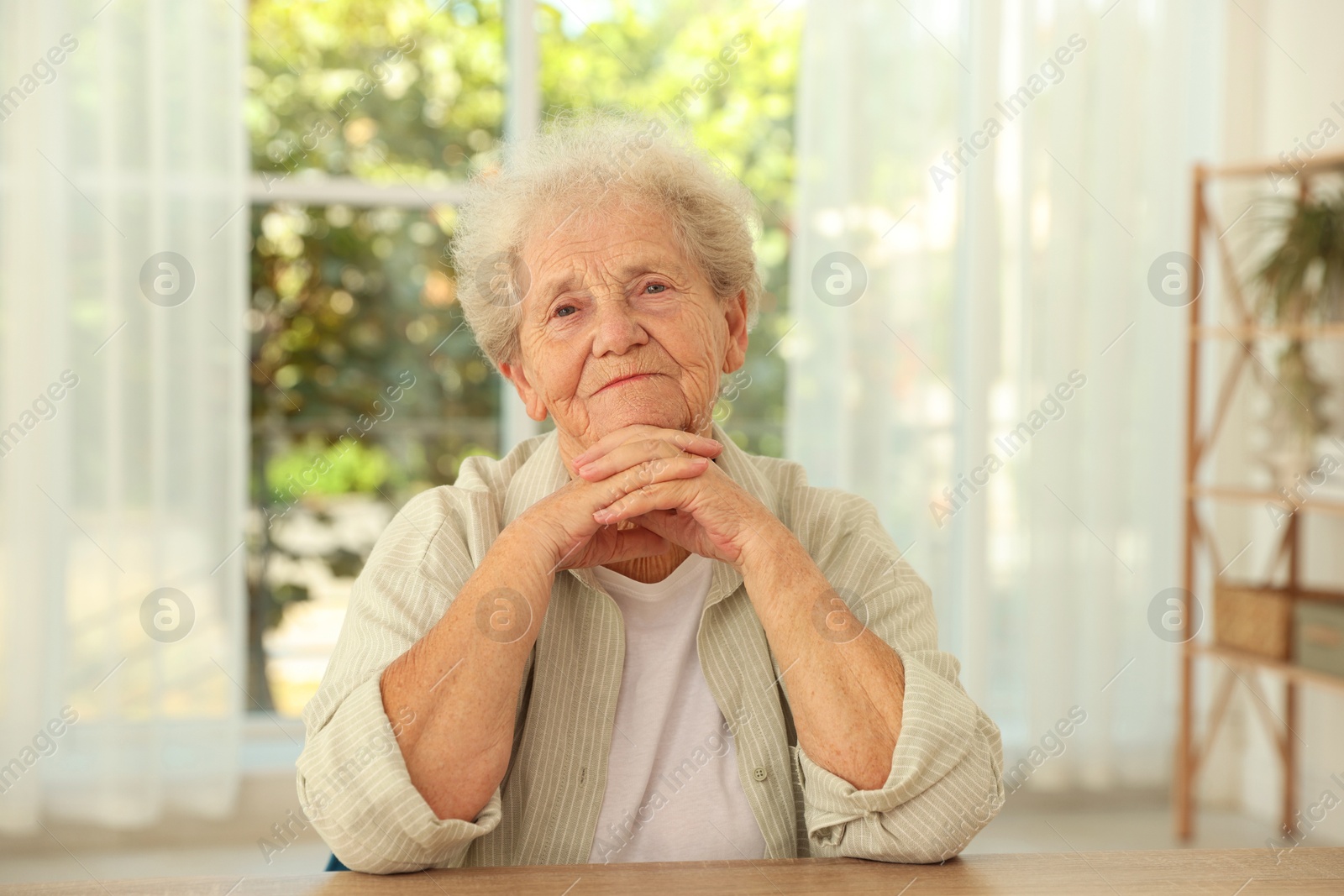 Photo of Portrait of beautiful senior woman at wooden table indoors