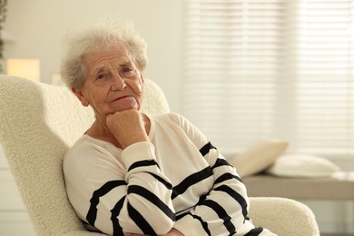 Beautiful senior woman sitting on armchair at home