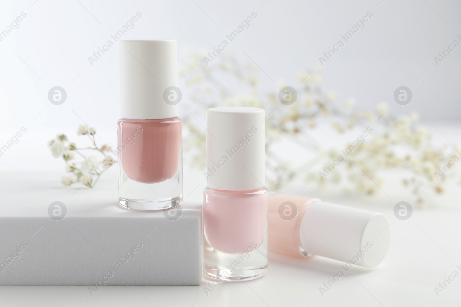 Photo of Nail polishes in bottles on white table, closeup