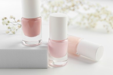 Photo of Nail polishes in bottles on white table, closeup