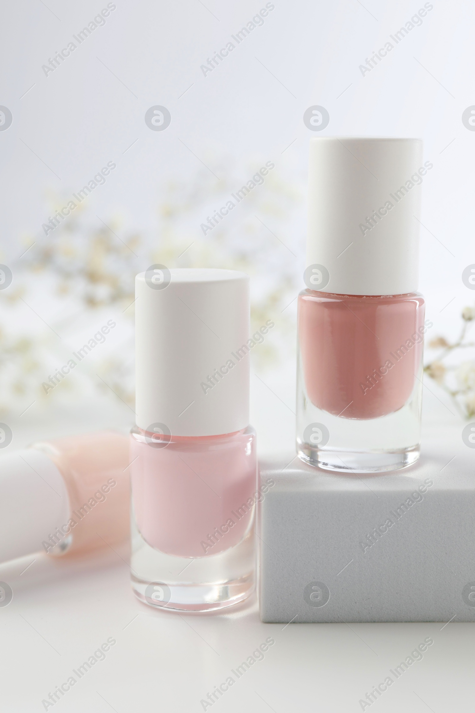 Photo of Nail polishes in bottles on white table, closeup