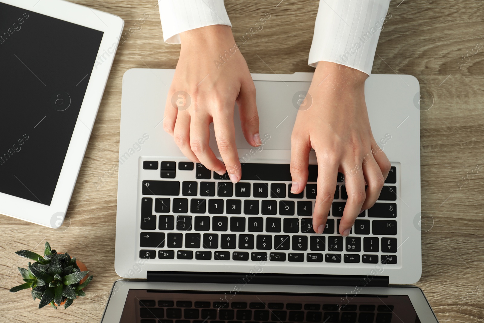 Photo of Businesswoman using laptop at wooden table indoors, top view. Modern technology