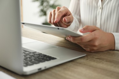 Photo of Businesswoman using tablet at wooden table indoors, closeup. Modern technology