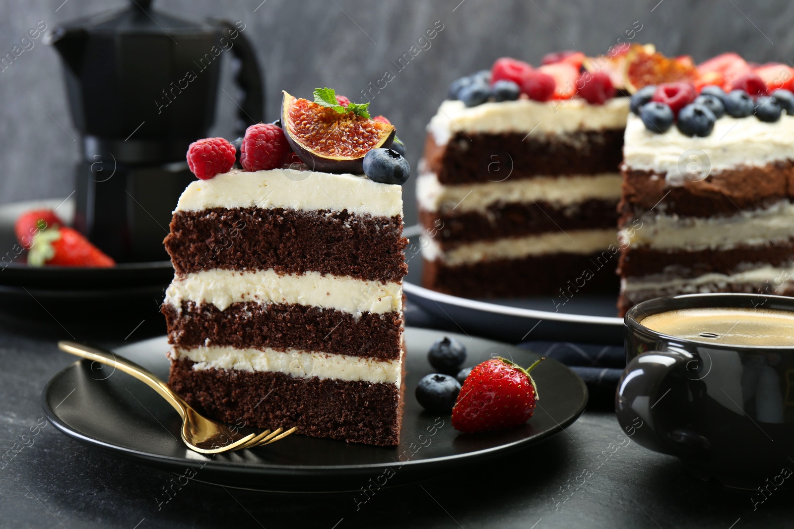 Photo of Piece of delicious chocolate sponge cake with berries and coffee on black table, closeup