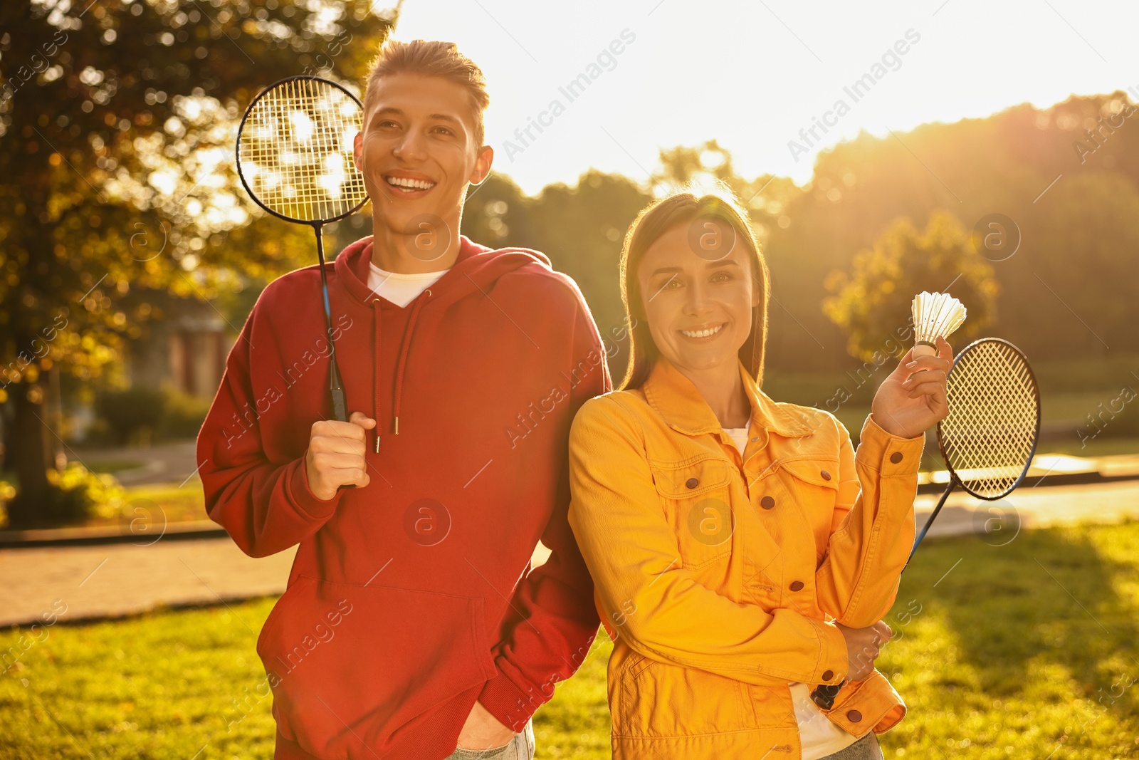 Photo of Young man and woman with badminton rackets and shuttlecock in park on sunny day