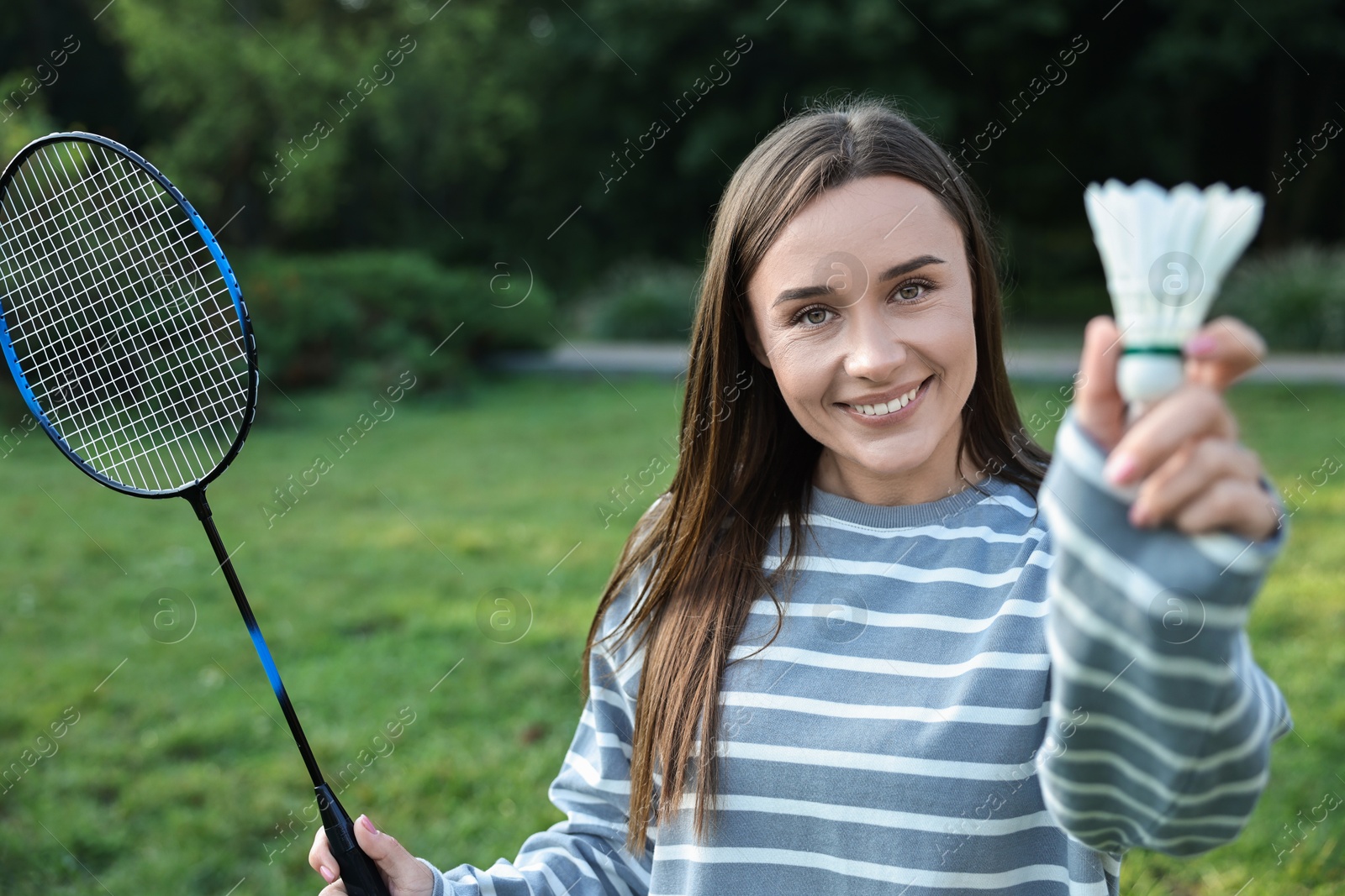 Photo of Happy young woman with badminton racket and shuttlecock in park