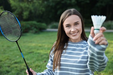 Photo of Happy young woman with badminton racket and shuttlecock in park