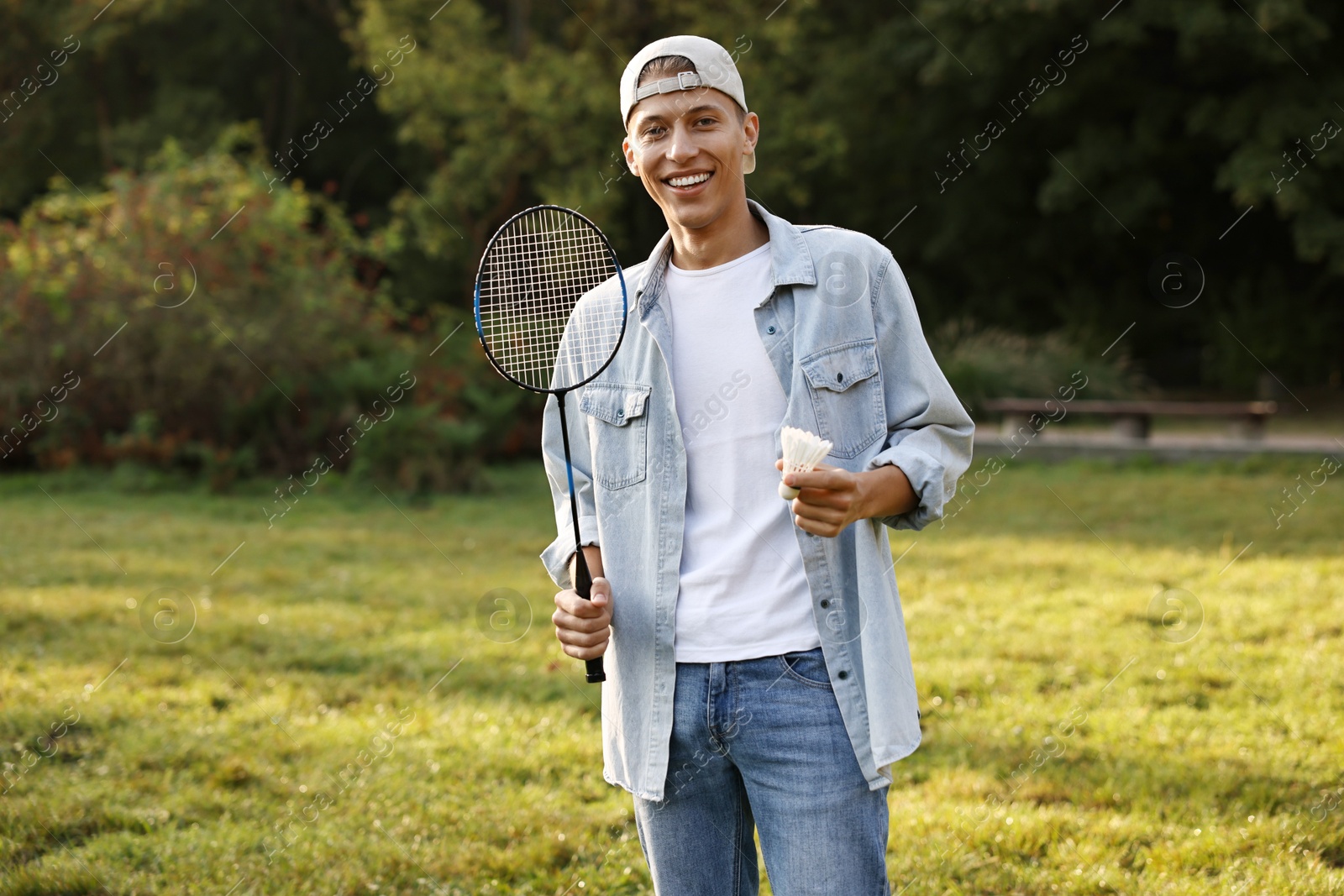 Photo of Happy young man with badminton racket and shuttlecock in park