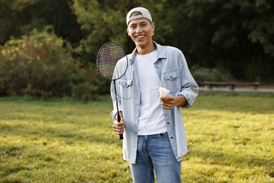 Photo of Happy young man with badminton racket and shuttlecock in park