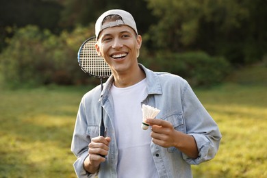 Photo of Happy young man with badminton racket and shuttlecock in park