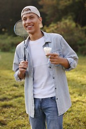 Photo of Happy young man with badminton racket and shuttlecock in park