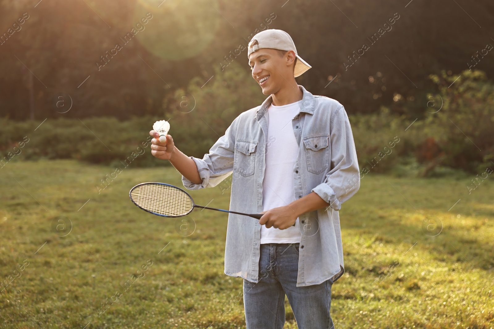 Photo of Happy young man with badminton racket and shuttlecock in park