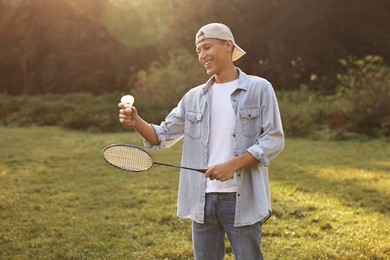 Happy young man with badminton racket and shuttlecock in park