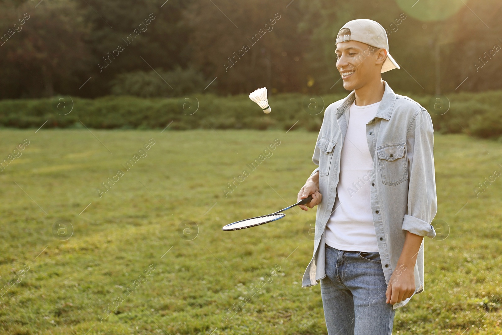 Photo of Young man playing badminton racket in park on sunny day