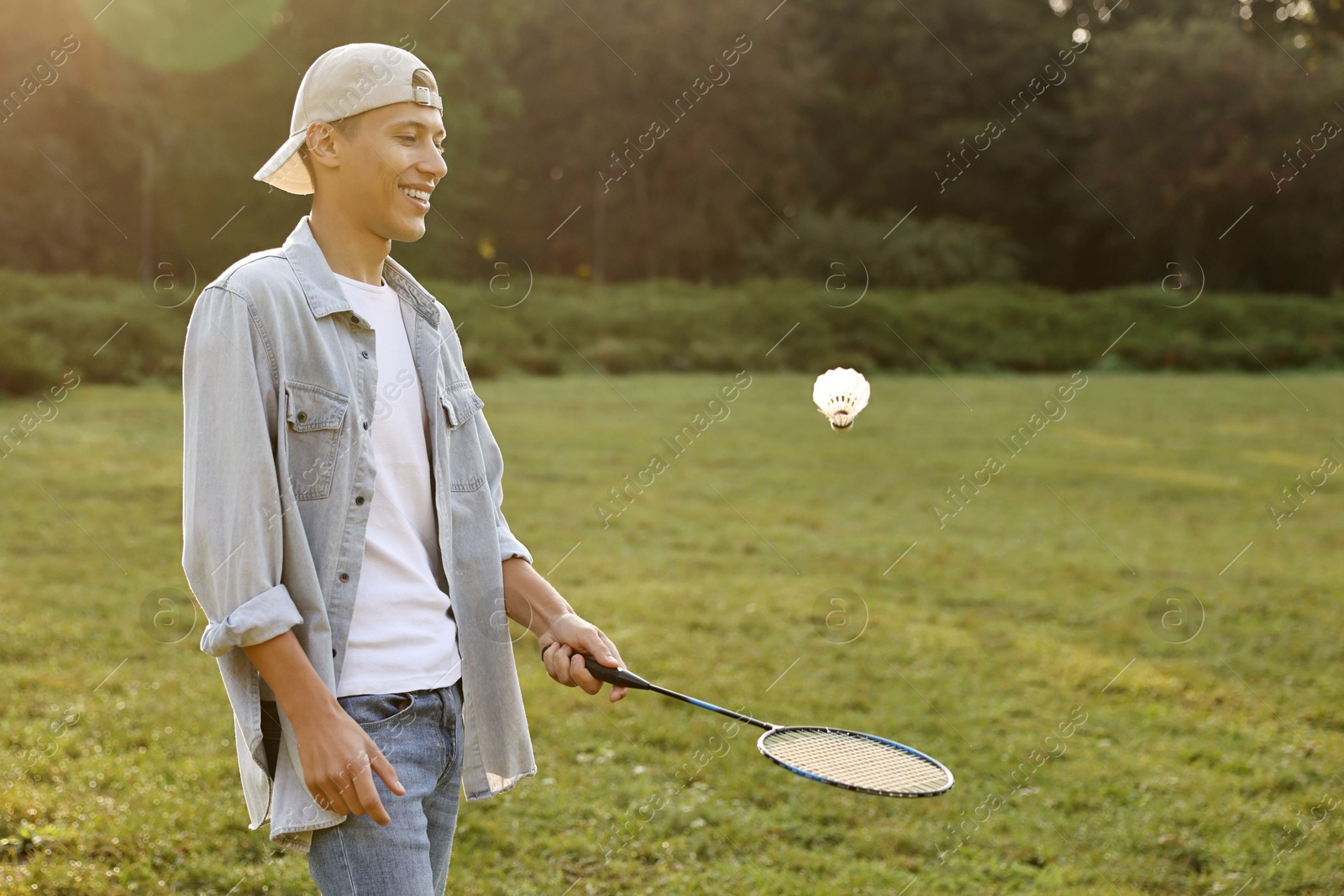 Photo of Young man playing badminton racket in park on sunny day