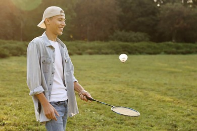 Young man playing badminton racket in park on sunny day