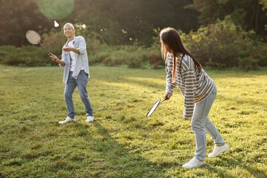 Photo of Young man and woman playing badminton in park on sunny day, selective focus