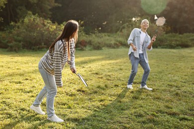 Young man and woman playing badminton in park on sunny day, selective focus