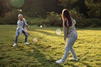 Photo of Young man and woman playing badminton in park on sunny day, selective focus