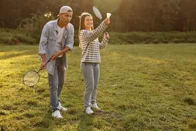 Photo of Young woman and man playing badminton in park on sunny day