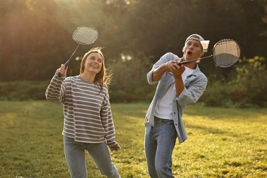 Photo of Young woman and man playing badminton in park on sunny day