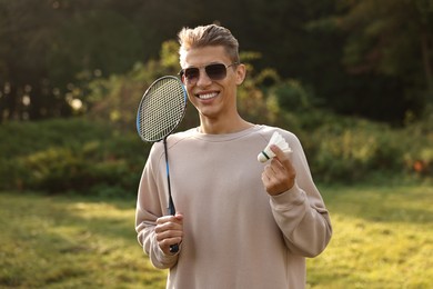 Photo of Happy young man with badminton racket and shuttlecock in park on sunny day