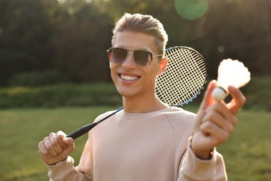 Photo of Happy young man with badminton racket and shuttlecock in park on sunny day