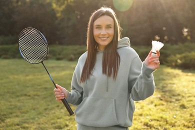 Photo of Happy young woman with badminton racket and shuttlecock in park on sunny day