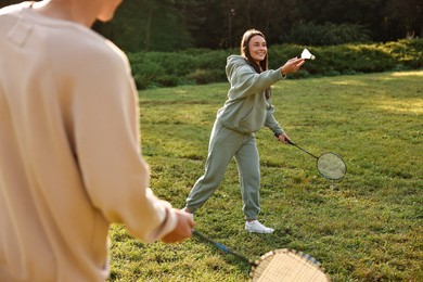 Photo of Young woman and man playing badminton in park on sunny day, selective focus