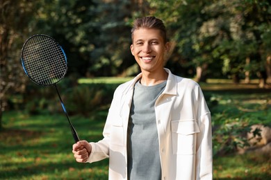 Happy young man with badminton racket in park